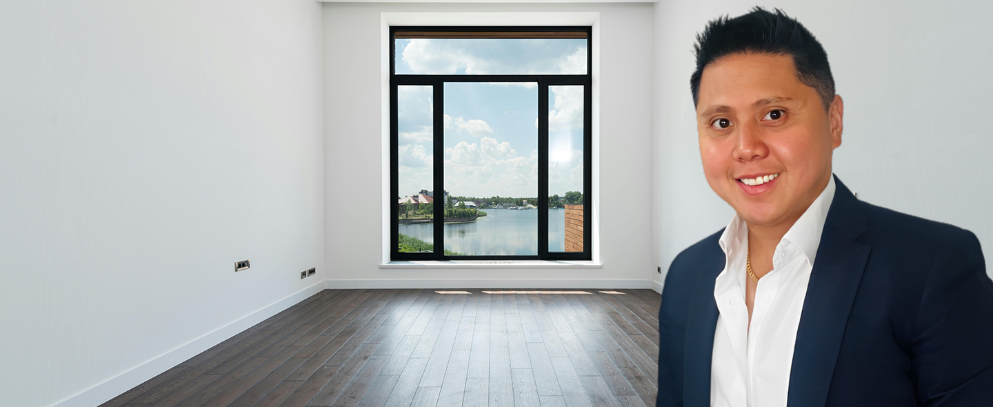 A man wearing a suit stands in an unoccupied room, embodying elegance and a professional demeanor.